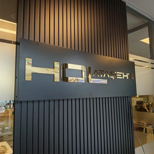 Ofis girişinde siyah panel üzerinde krom harfli duvar logosu