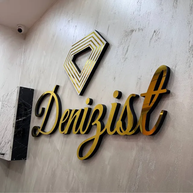 Beyaz duvar üzerinde aynalı gold harf ve logo