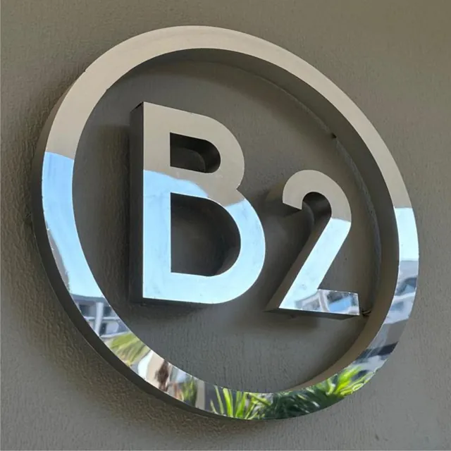 Duvarda krom çember içinde krom harfli ışıksız logo