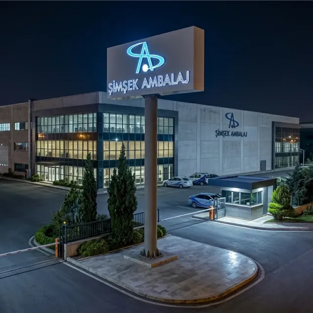 Fabrika girişinde ışıklı logolu totem tabela, gece