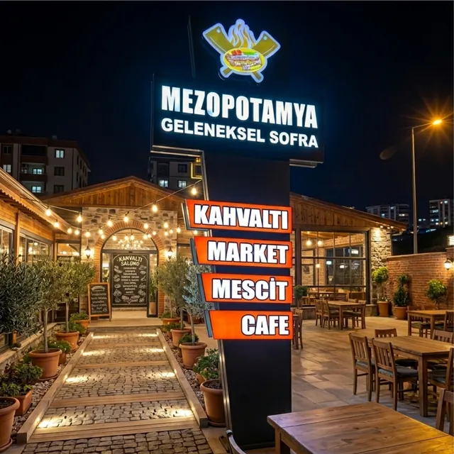 Restoran bahçesinde ışıklı bölüm panelli totem tabela, gece